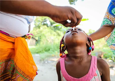 Child with head tilted back receiving oral polio vaccine 